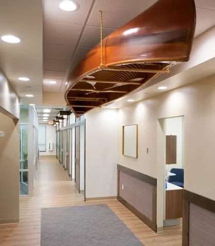 A wooden canoe hung from the ceiling of a corridor between treatment rooms.