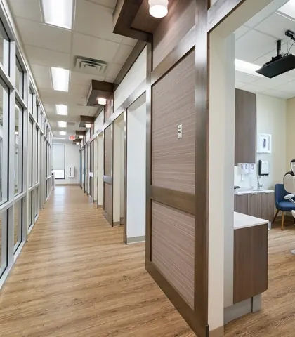 The treatment corridor, glass-fronted rooms on one side and a treatment chair by a window.