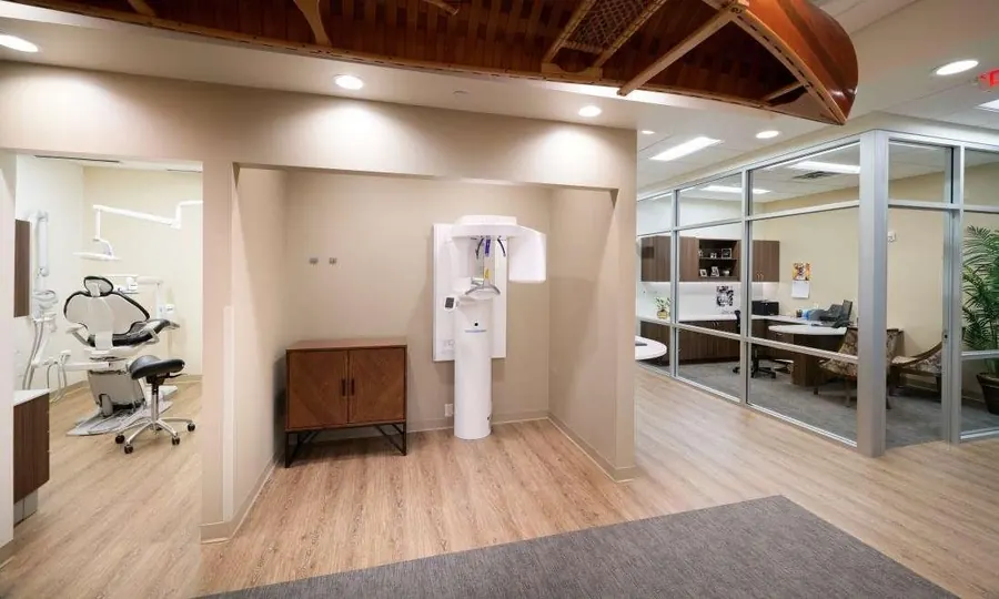 The imaging alcove at Woodbury Dental Care: a standing 3-D cone beam unit, with a treatment room to the left and a glass-walled office to the right.