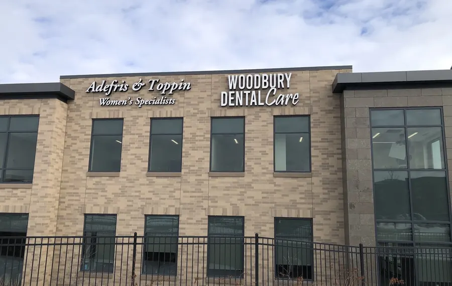 The Woodbury Dental Care sign on the brick front of the building at 215 Radio Drive, in winter.